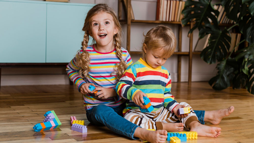 Kindesunterhalt: Zwei jüngere Kinder, die auf der Erde sitzen und spielen.